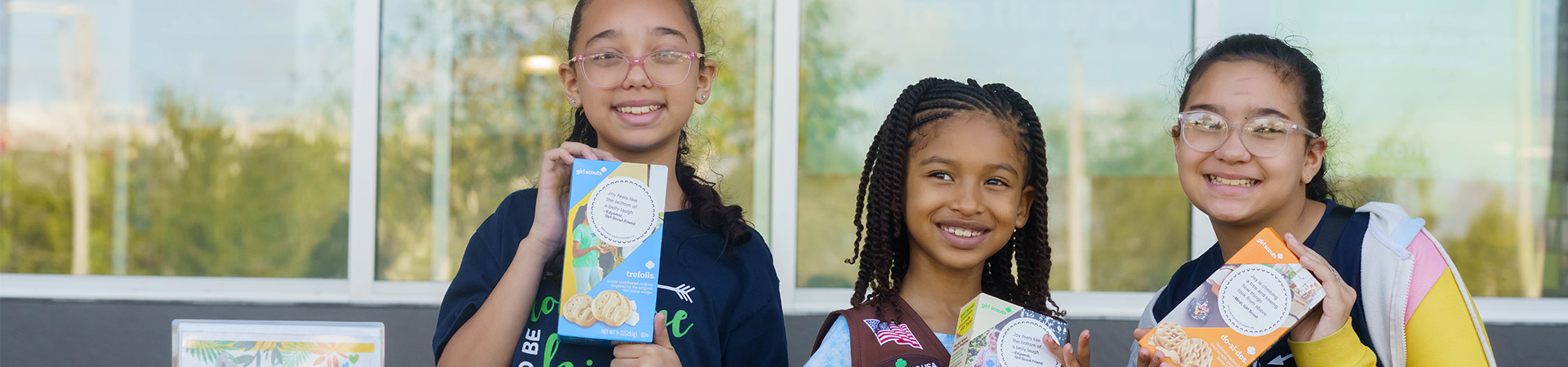  Two girl scouts holding up girl scout cookies 