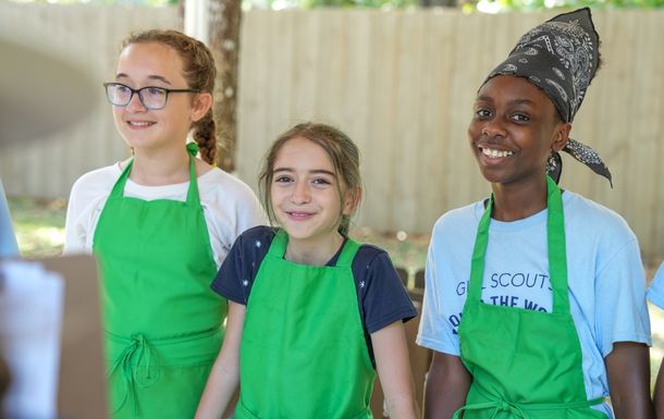 girl scout with digital camera outside wearing trefoil baseball cap