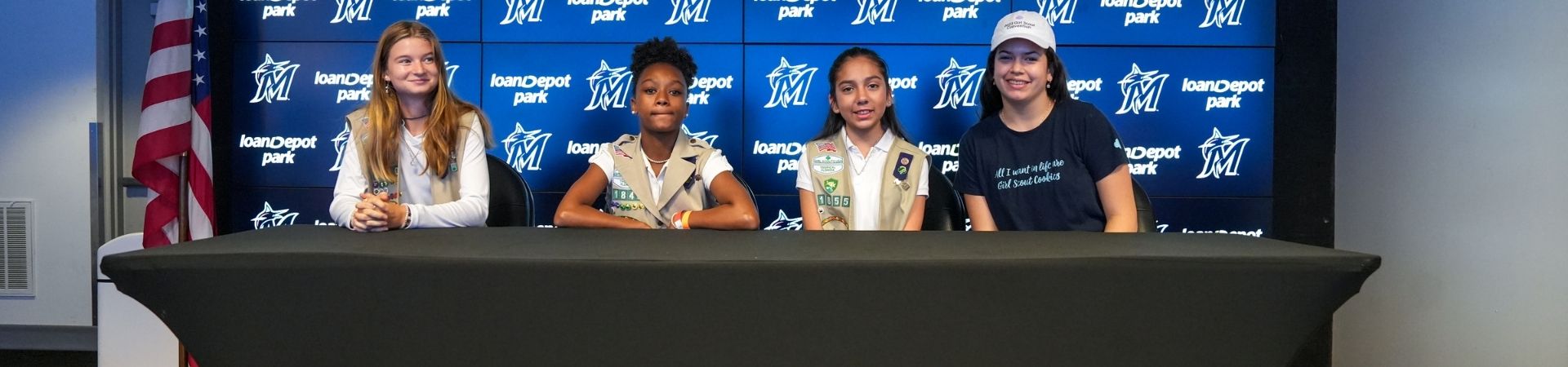  high school girl in senior ambassador sash smiling at daisy in vest uniforms with pins and badges displayed 