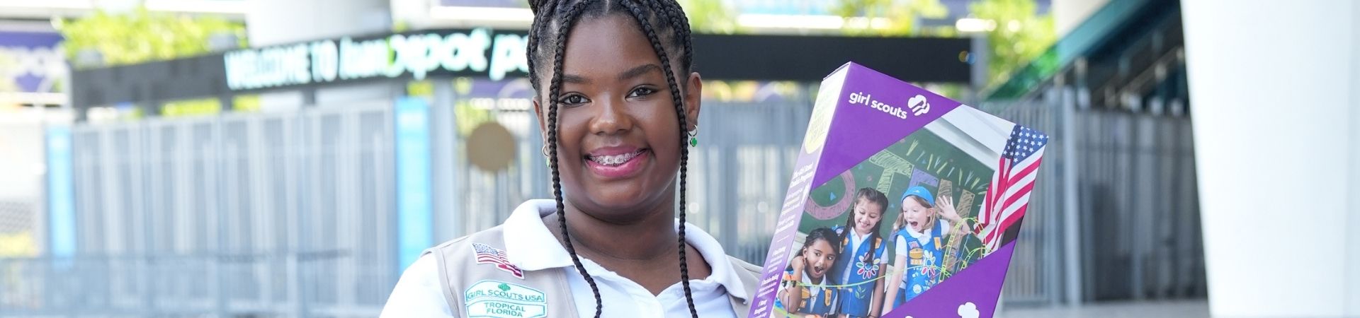  girl scout wearing uniform selling cookies at cookie booth 