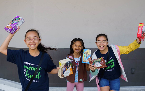 girl scout putting boxes of trefoils into cookie transport bag