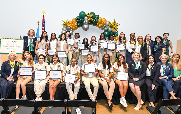 ambassador high school girl scout wearing sash outside against green background