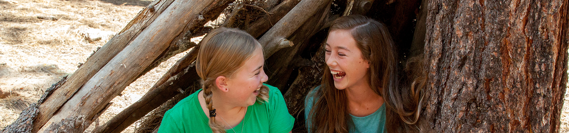  Girl Scouts laughing outside in tree fort 