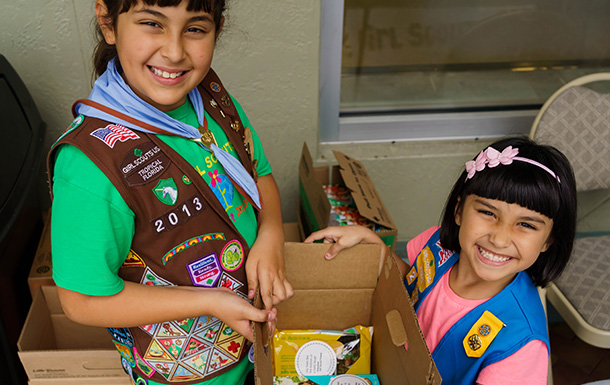 girl scout putting boxes of trefoils into cookie transport bag