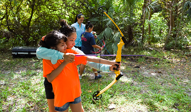 Troop leader with two Girl Scouts smiling outdoors