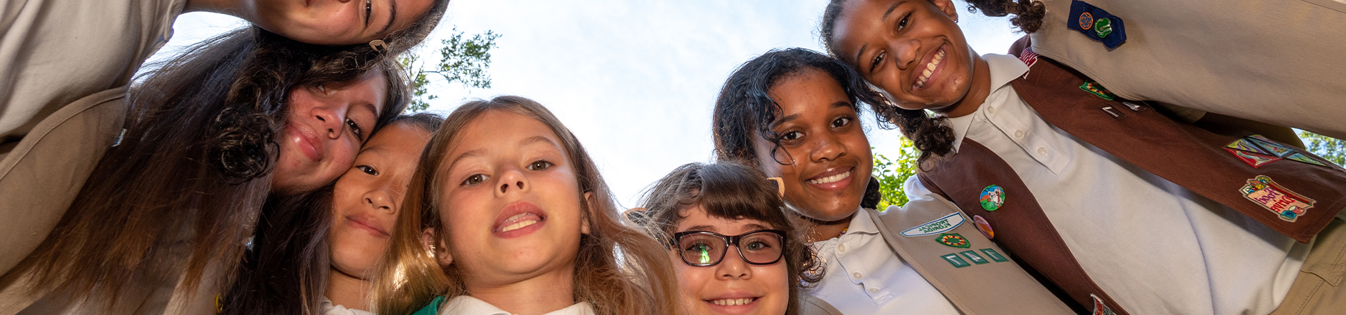  Girl Scouts smiling at each other outside 