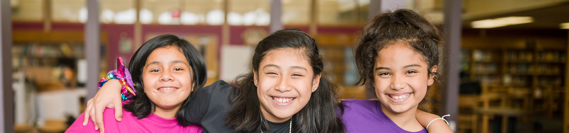  three young girl scouts with their arms wrapped around one another and smiling at the camera 